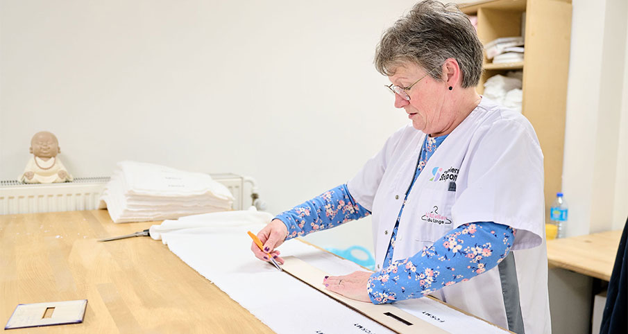 Une travailleuse prend les mesures pour faire les retouches sur un vêtement