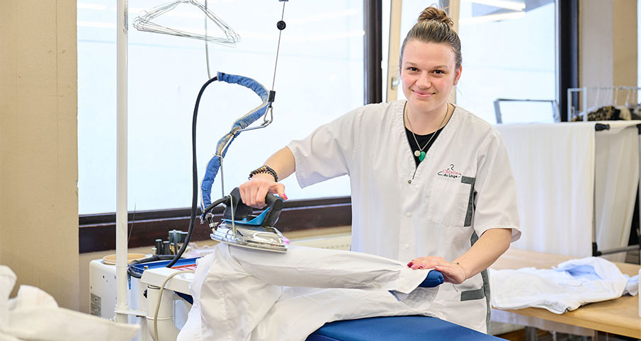 Une travailleuse en train de repasser un vêtement blanc