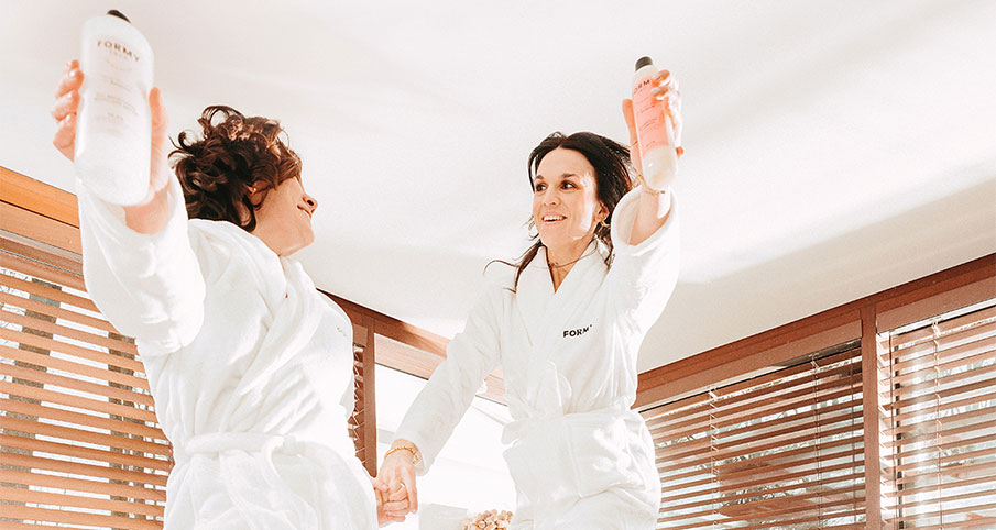 Deux femmes portant un peignoir blanc Formy et elles ont chacune un produit Formy dans la main