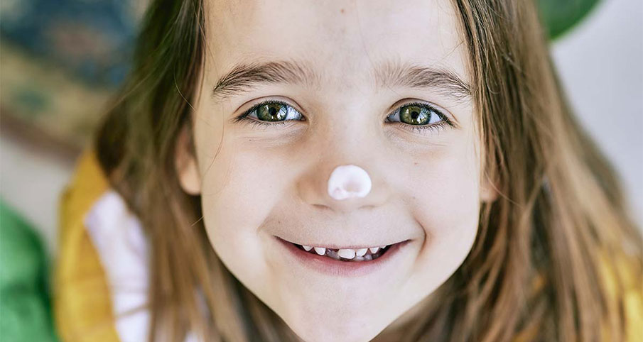 Une petite fille souriante qui a du shampoing sur le bout de son nez