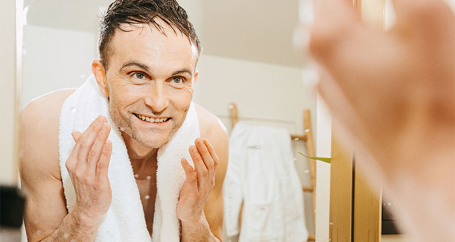 Un homme avec une serviette autour du cou se regardant dans le miroir