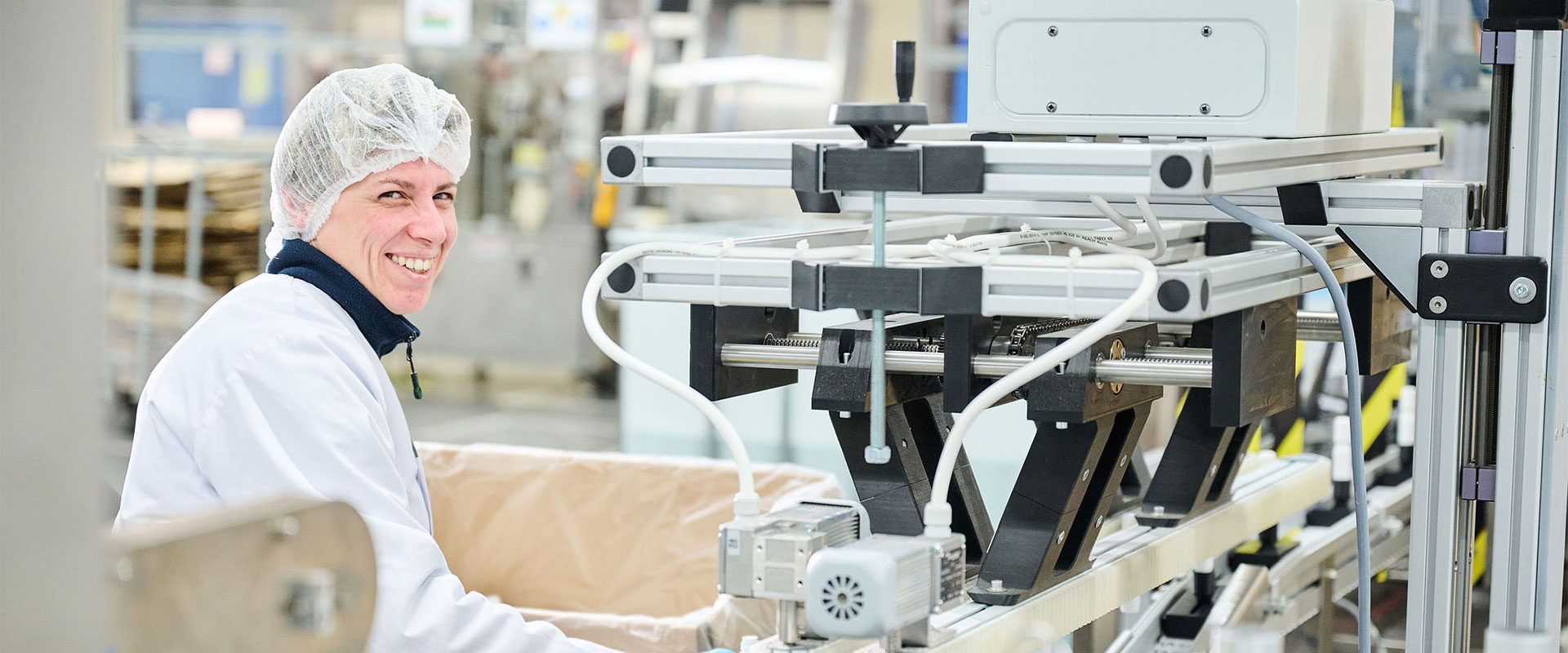 le-saupont-recrutement-bandeau Une personne portant un équipement de travail qui travaille à proximité de machines automatisées au sein de la chaîne de production