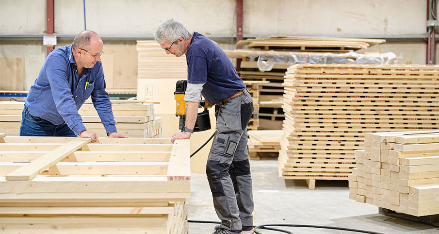 Deux hommes sont appuyés sur des grandes palettes en bois