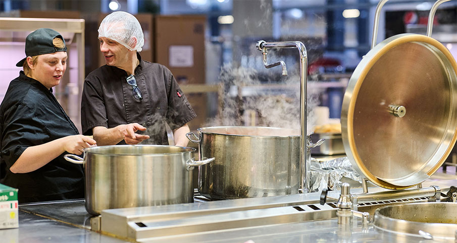 Des travailleurs préparent des plats dans la cuisine de "La Table des Ateliers"